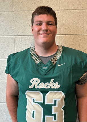 A young man wearing a white and black jersey with the number 14 on it. Description generated by AI