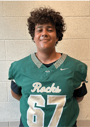 A young man wearing a white and black jersey with the number 14 on it. Description generated by AI