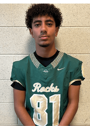 A young man wearing a white and black jersey with the number 14 on it. Description generated by AI