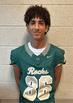 A young man wearing a white and black jersey with the number 14 on it. Description generated by AI
