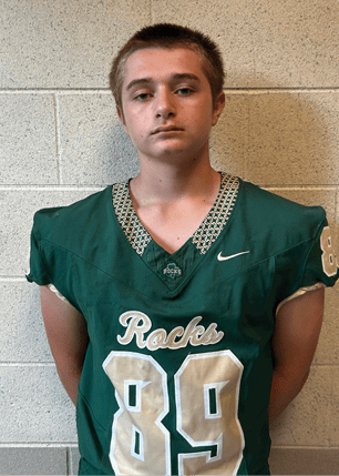 A young man wearing a white and black jersey with the number 14 on it. Description generated by AI