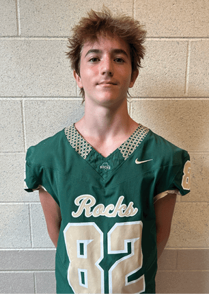 A young man wearing a white and black jersey with the number 14 on it. Description generated by AI