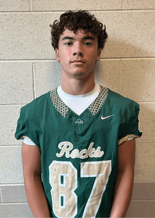 A young man wearing a white and black jersey with the number 14 on it. Description generated by AI