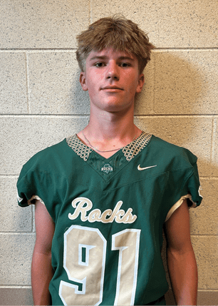 A young man wearing a white and black jersey with the number 14 on it. Description generated by AI
