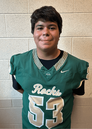 A young man wearing a white and black jersey with the number 14 on it. Description generated by AI