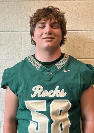 A young man wearing a white and black jersey with the number 14 on it. Description generated by AI