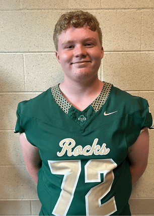 A young man wearing a white and black jersey with the number 14 on it. Description generated by AI