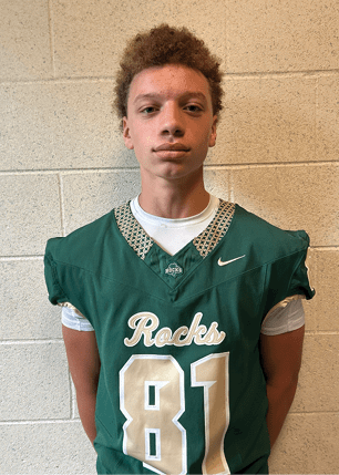 A young man wearing a white and black jersey with the number 14 on it. Description generated by AI