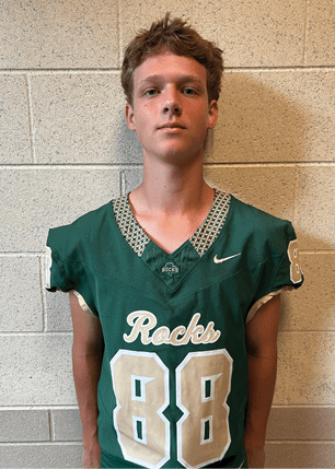 A young man wearing a white and black jersey with the number 14 on it. Description generated by AI