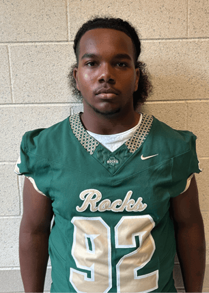 A young man wearing a white and black jersey with the number 14 on it. Description generated by AI
