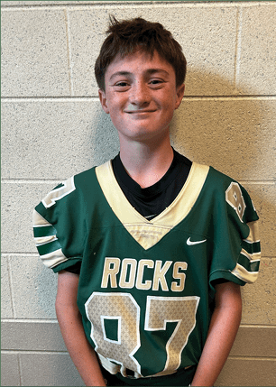 A young man wearing a white and black jersey with the number 14 on it. Description generated by AI