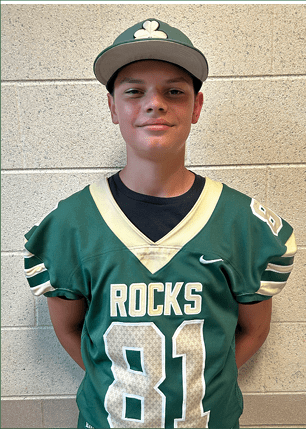 A young man wearing a white and black jersey with the number 14 on it. Description generated by AI