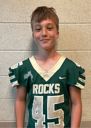 A young man wearing a white and black jersey with the number 14 on it. Description generated by AI