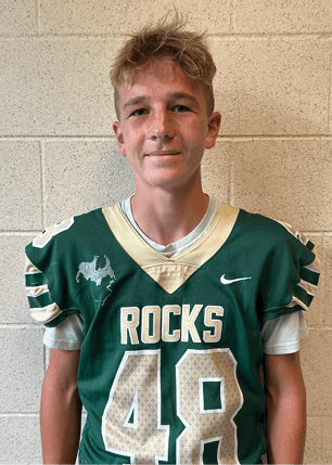 A young man wearing a white and black jersey with the number 14 on it. Description generated by AI