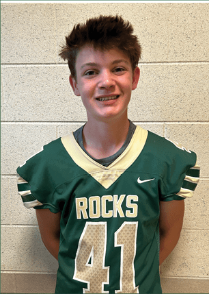 A young man wearing a white and black jersey with the number 14 on it. Description generated by AI
