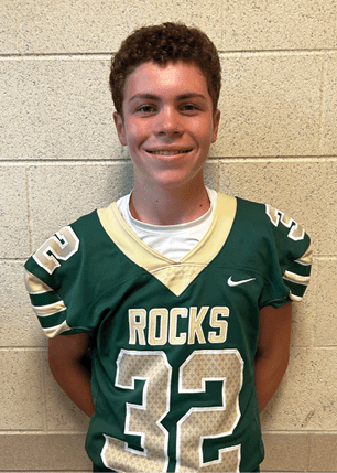 A young man wearing a white and black jersey with the number 14 on it. Description generated by AI
