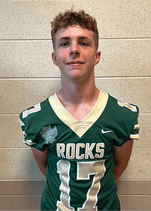 A young man wearing a white and black jersey with the number 14 on it. Description generated by AI