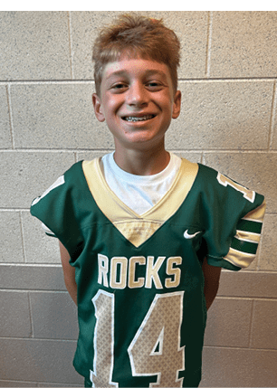A young man wearing a white and black jersey with the number 14 on it. Description generated by AI