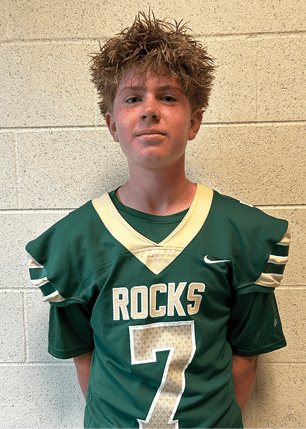 A young man wearing a white and black jersey with the number 14 on it. Description generated by AI