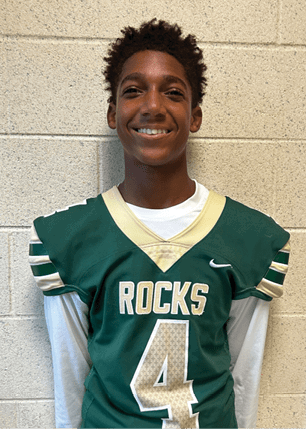 A young man wearing a white and black jersey with the number 14 on it. Description generated by AI