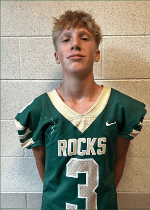 A young man wearing a white and black jersey with the number 14 on it. Description generated by AI