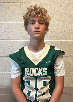 A young man wearing a white and black jersey with the number 14 on it. Description generated by AI