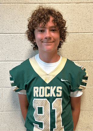 A young man wearing a white and black jersey with the number 14 on it. Description generated by AI