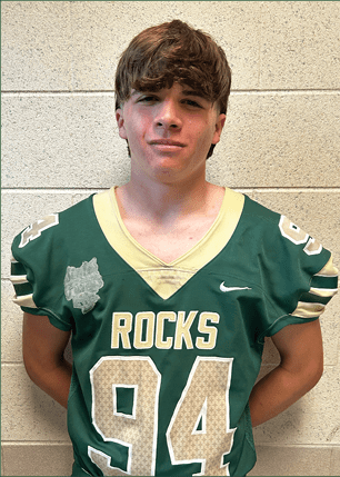 A young man wearing a white and black jersey with the number 14 on it. Description generated by AI