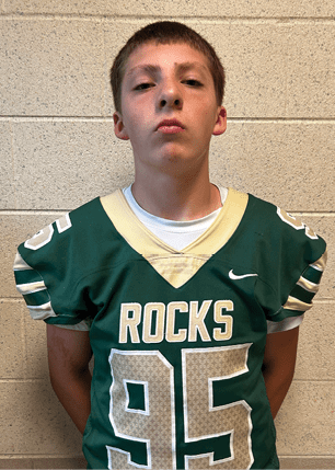 A young man wearing a white and black jersey with the number 14 on it. Description generated by AI