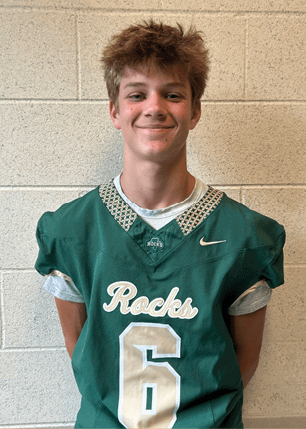 A young man wearing a white and black jersey with the number 14 on it. Description generated by AI