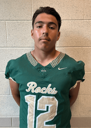 A young man wearing a white and black jersey with the number 14 on it. Description generated by AI