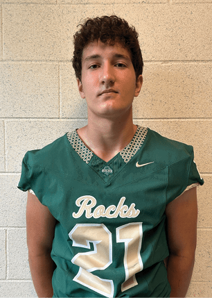 A young man wearing a white and black jersey with the number 14 on it. Description generated by AI