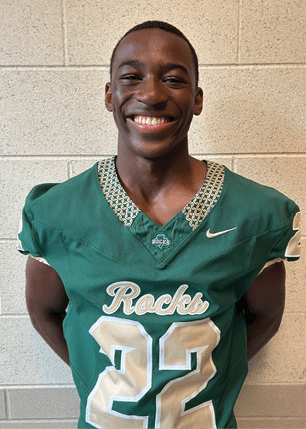 A young man wearing a white and black jersey with the number 14 on it. Description generated by AI