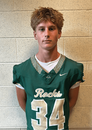 A young man wearing a white and black jersey with the number 14 on it. Description generated by AI