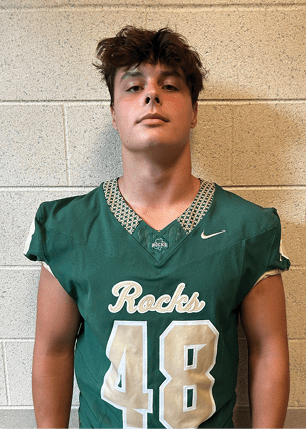 A young man wearing a white and black jersey with the number 14 on it. Description generated by AI