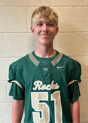A young man wearing a white and black jersey with the number 14 on it. Description generated by AI