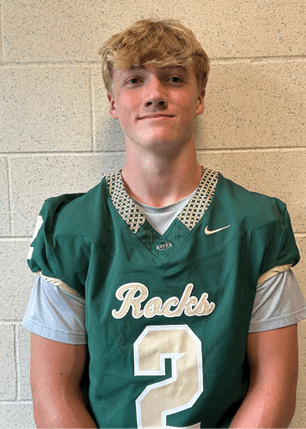 A young man wearing a white and black jersey with the number 14 on it. Description generated by AI