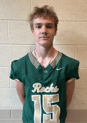 A young man wearing a white and black jersey with the number 14 on it. Description generated by AI