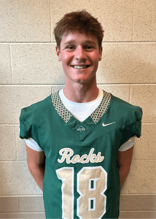 A young man wearing a white and black jersey with the number 14 on it. Description generated by AI