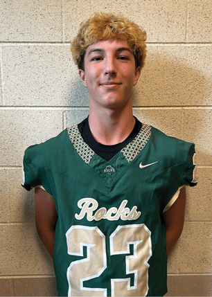 A young man wearing a white and black jersey with the number 14 on it. Description generated by AI