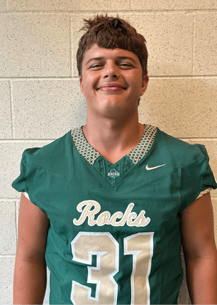 A young man wearing a white and black jersey with the number 14 on it. Description generated by AI