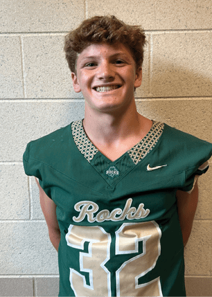 A young man wearing a white and black jersey with the number 14 on it. Description generated by AI