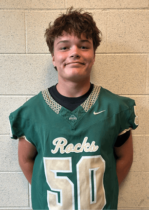 A young man wearing a white and black jersey with the number 14 on it. Description generated by AI