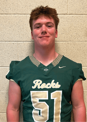 A young man wearing a white and black jersey with the number 14 on it. Description generated by AI