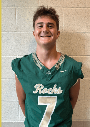 A young man wearing a white and black jersey with the number 14 on it. Description generated by AI