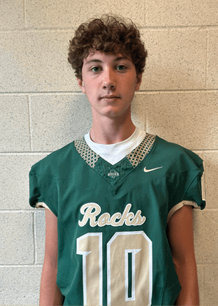 A young man wearing a white and black jersey with the number 14 on it. Description generated by AI