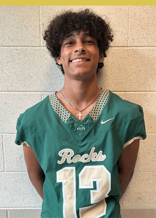 A young man wearing a white and black jersey with the number 14 on it. Description generated by AI