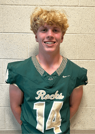 A young man wearing a white and black jersey with the number 14 on it. Description generated by AI