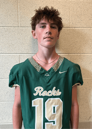 A young man wearing a white and black jersey with the number 14 on it. Description generated by AI