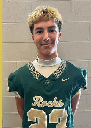 A young man wearing a white and black jersey with the number 14 on it. Description generated by AI